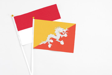 Bhutan and Indonesia stick flags on white background. High quality fabric, miniature national flag. Peaceful global concept.White floor for copy space.