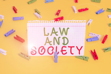 Handwriting text Law And Society. Conceptual photo Address the mutual relationship between law and society Colored clothespin papers empty reminder yellow floor background office