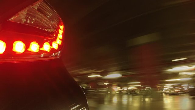 Close-up of the tail lights of a car moving in time lapsed inside a large garage, the speed of the camera used causes an effect of textures, time passing and fantasy to the image