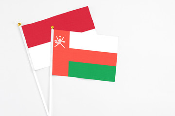 Oman and Indonesia stick flags on white background. High quality fabric, miniature national flag. Peaceful global concept.White floor for copy space.