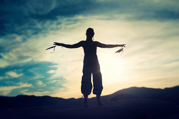 Fototapeta na wymiar Shamanic Movement Woman on Big Boulders desert twilight feather qi gong