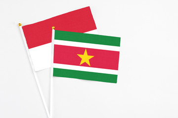 Suriname and Indonesia stick flags on white background. High quality fabric, miniature national flag. Peaceful global concept.White floor for copy space.