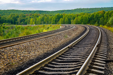 Fototapeta na wymiar rails of the railway go into the distance, turn left, bright summer landscape, nobody