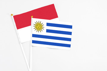 Uruguay and Indonesia stick flags on white background. High quality fabric, miniature national flag. Peaceful global concept.White floor for copy space.