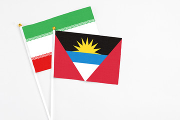 Antigua and Barbuda and Iran stick flags on white background. High quality fabric, miniature national flag. Peaceful global concept.White floor for copy space.