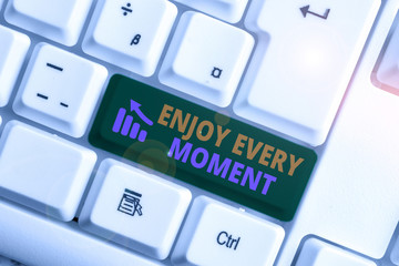 Writing note showing Enjoy Every Moment. Business concept for being pleased with your life Have fun Precious time White pc keyboard with note paper above the white background