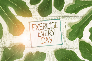 Handwriting text Exercise Every Day. Conceptual photo move body energetically in order to get fit and healthy Leaves surrounding notepaper above a classic wooden table as the background