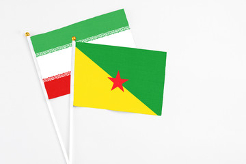 French Guiana and Iran stick flags on white background. High quality fabric, miniature national flag. Peaceful global concept.White floor for copy space.