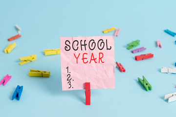 Handwriting text School Year. Conceptual photo the annual period of sessions of an educational institution Colored clothespin rectangle square shaped paper light blue background