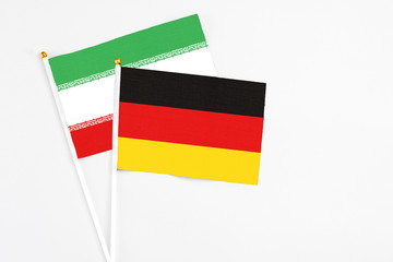 Germany and Iran stick flags on white background. High quality fabric, miniature national flag. Peaceful global concept.White floor for copy space.