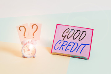 Word writing text Good Credit. Business photo showcasing borrower has a relatively high credit score and safe credit risk Mini size alarm clock beside a Paper sheet placed tilted on pastel backdrop