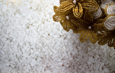 Yellow flowers from beads on a decorative background. Golden background.