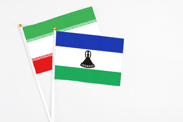 Lesotho and Iran stick flags on white background. High quality fabric, miniature national flag. Peaceful global concept.White floor for copy space.