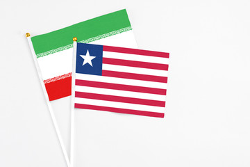 Liberia and Iran stick flags on white background. High quality fabric, miniature national flag. Peaceful global concept.White floor for copy space.