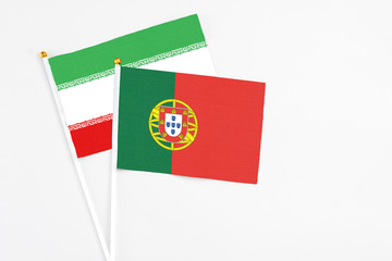 Portugal and Iran stick flags on white background. High quality fabric, miniature national flag. Peaceful global concept.White floor for copy space.