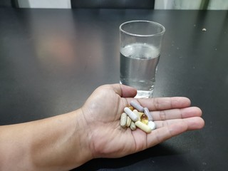pills in hand and glass water
