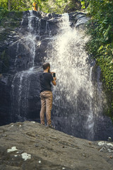 Obraz premium Human standing on the big stone opposite wild nature waterfall view
