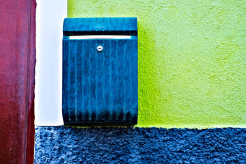 Dark blue mailbox on a colorful wall.
