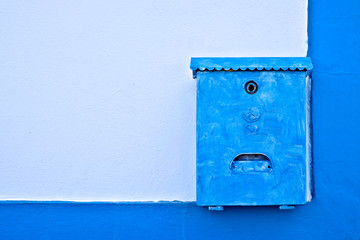 Old blue letter box on a blue wall.