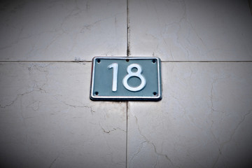 Number 18, eighteen, blue blate on pale background, vignette effect.