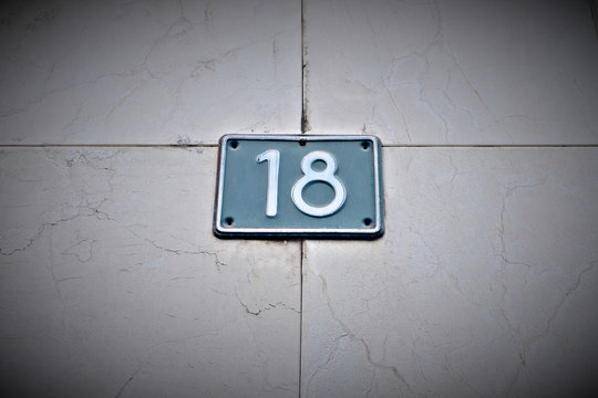 Number 18, eighteen, blue blate on pale background, vignette effect.