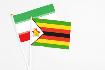 Zimbabwe and Iran stick flags on white background. High quality fabric, miniature national flag. Peaceful global concept.White floor for copy space.
