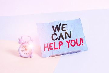 Writing note showing We Can Help You. Business concept for offering good assistance to customers or friends Alarm clock beside a Paper sheet placed on pastel backdrop
