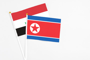 North Korea and Iraq stick flags on white background. High quality fabric, miniature national flag. Peaceful global concept.White floor for copy space.