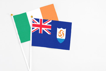 Fototapeta premium Anguilla and Ireland stick flags on white background. High quality fabric, miniature national flag. Peaceful global concept.White floor for copy space