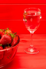 strawberries on red wooden background and water