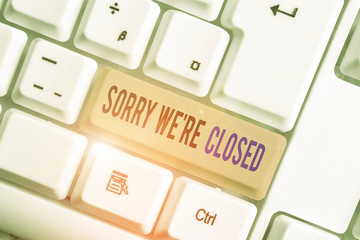 Text sign showing Sorry We Re Closed. Business photo text Expression of Regret Disappointment Not Open Sign White pc keyboard with empty note paper above white background key copy space