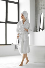 Young woman with towel in light bathroom
