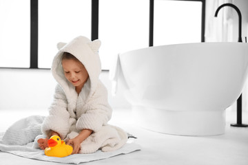 Cute little girl near tub in bathroom. Space for text