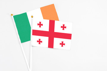Georgia and Ireland stick flags on white background. High quality fabric, miniature national flag. Peaceful global concept.White floor for copy space