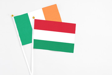 Hungary and Ireland stick flags on white background. High quality fabric, miniature national flag. Peaceful global concept.White floor for copy space