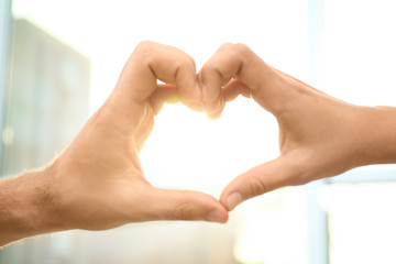 Young people forming heart with hands indoors, closeup. Happy family