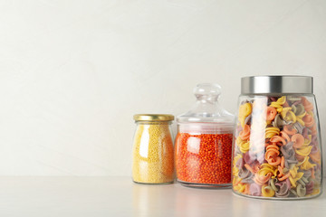 Glass jars with different types of groats on white wooden table