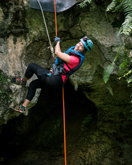 A female traveler goes rappelling into a cave in Puerto Rico - obrazy, fototapety, plakaty