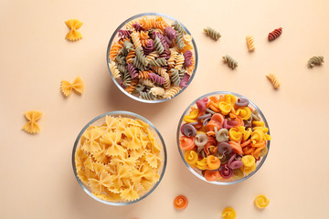 Different types of pasta on beige background, flat lay