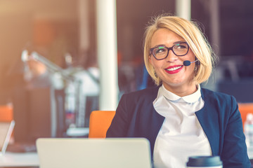 Customer service representative at work. Beautiful young woman in headset working at the computer