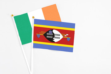 Swaziland and Ireland stick flags on white background. High quality fabric, miniature national flag. Peaceful global concept.White floor for copy space