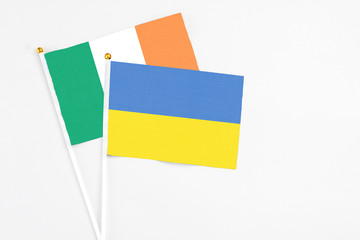Ukraine and Ireland stick flags on white background. High quality fabric, miniature national flag. Peaceful global concept.White floor for copy space
