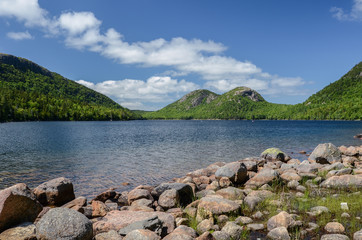 The rounded peaks of The Bubbles above Jordan Pond under blue sky and clouds in Acadia National Park, Maine, USA