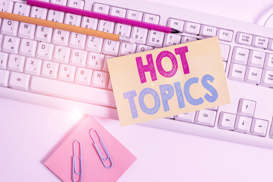 Conceptual hand writing showing Hot Topics. Concept meaning subject that a lot of showing are arguing and discussing White keyboard with note paper and clips on white background
