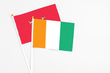 Cote D'Ivoire and Isle Of Man stick flags on white background. High quality fabric, miniature national flag. Peaceful global concept.White floor for copy space.