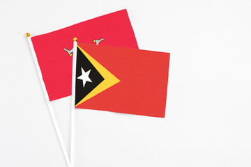 East Timor and Isle Of Man stick flags on white background. High quality fabric, miniature national flag. Peaceful global concept.White floor for copy space.