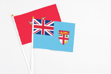 Fototapeta premium Fiji and Isle Of Man stick flags on white background. High quality fabric, miniature national flag. Peaceful global concept.White floor for copy space.