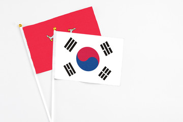 South Korea and Isle Of Man stick flags on white background. High quality fabric, miniature national flag. Peaceful global concept.White floor for copy space.