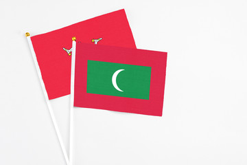 Maldives and Isle Of Man stick flags on white background. High quality fabric, miniature national flag. Peaceful global concept.White floor for copy space.