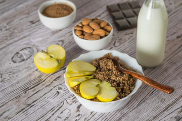 Apple slices with quinoa and cocoa porridge on a wooden table.